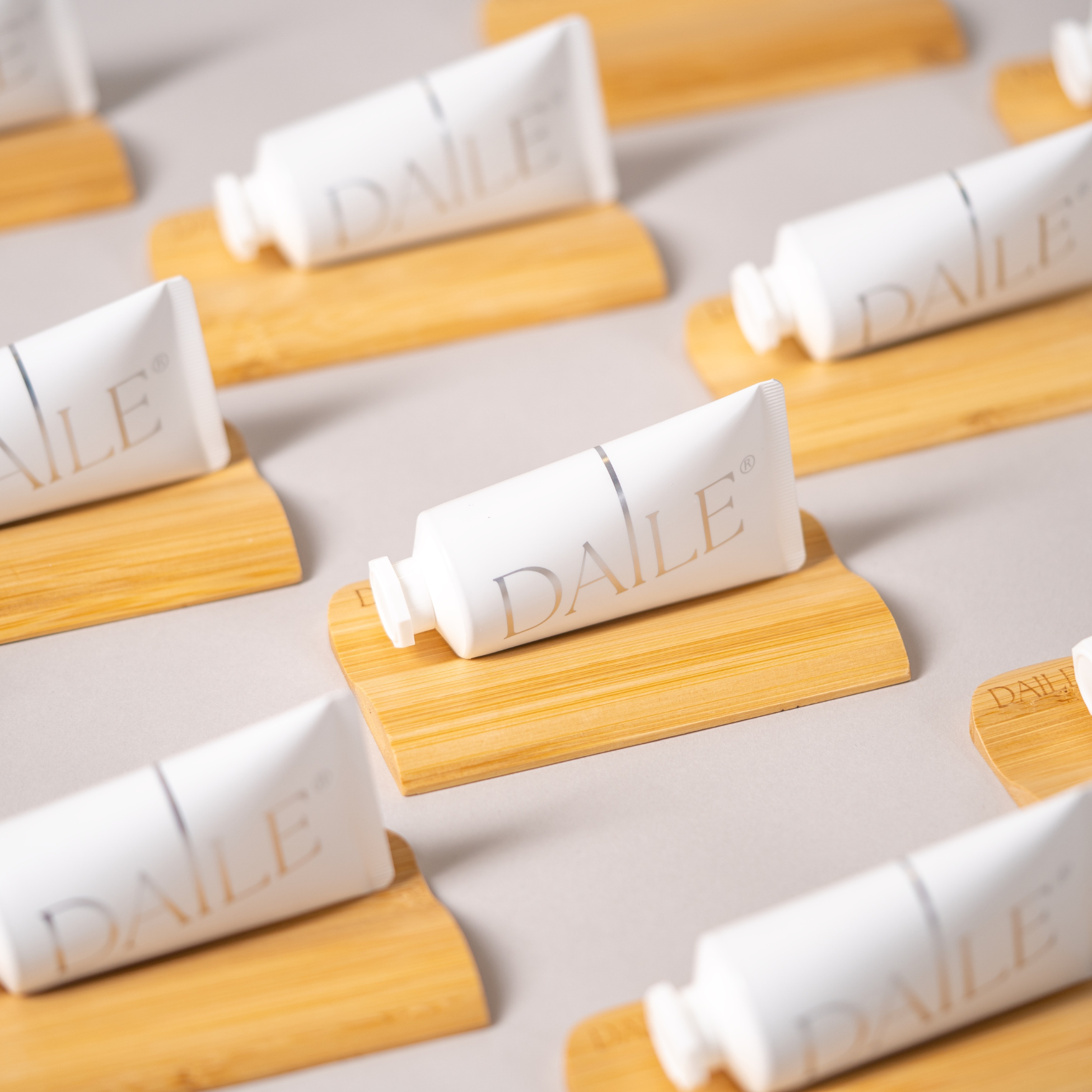 White DAILE art supply tubes on wooden holders in a neat, repeated arrangement