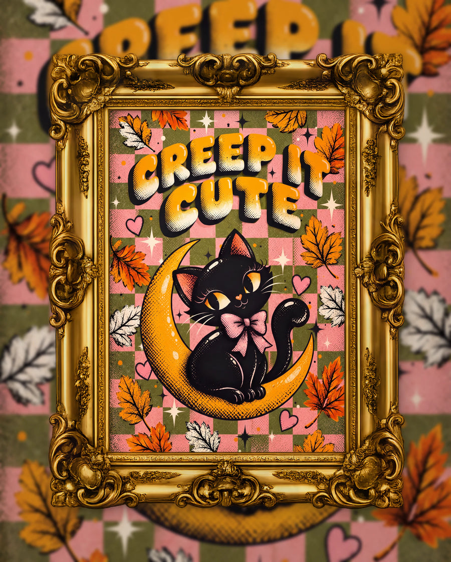 Creep It Cute, an original DAILE Studio Halloween artwork in an ornate gold frame — retro poster of a black cat with a pink bow on a golden crescent moon over pink and olive checks, lettering reading Creep It Cute.