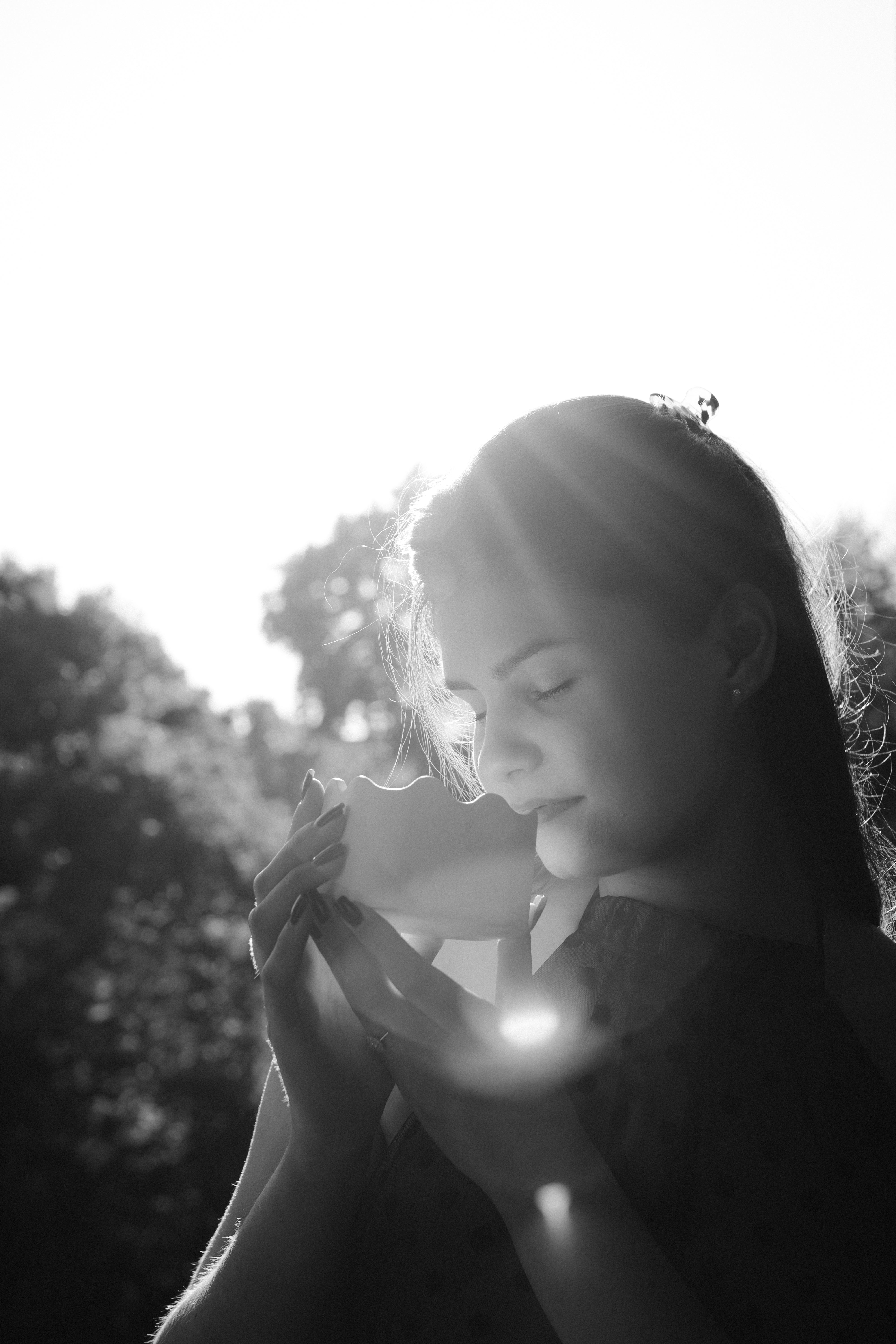 Woman holding art puzzle piece with sunlight, serene outdoor moment